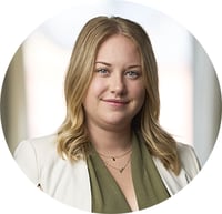 blond leende kvinna med vit kavaj och grön blus